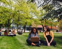 Students sat on the grass talking and working