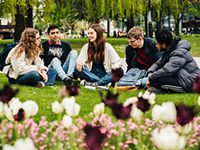 five students sitting outside on grass