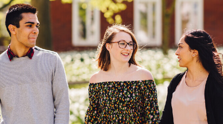 3 students walking on campus in the summer